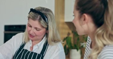 Orta yaşlı bir kadın ev yapımı gnocchi hazırlarken modern yeni mutfakta yaşlı bir anneyle durup komik bir hikaye anlatmaktan zevk duyardı. .