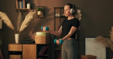 Formda kız eğitimi, egzersiz, spor yapma, müzik dinleme, dambıllar ellerinde. Uzay odasının ortasında dikiliyorlar..