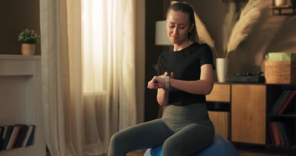 Fit Woman Sits Exercise Ball Checks Progress Smart Watch Counts — Stock Video