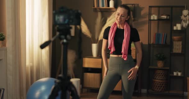 有影响力的人的确是通过在家的训练 冥想和瑜伽为社交网络而生活的 这个女人用相机和三脚架来记录练习 运动服广告 — 图库视频影像