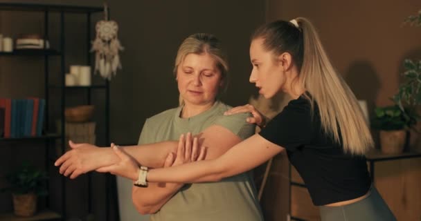 Kobieta Średnim Wieku Trenuje Domu Fizjoterapeutą Młoda Opiekunka Dziewczyna Rozciągająca — Wideo stockowe