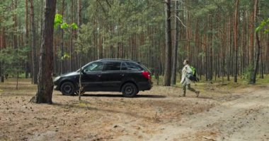 Ormanın ortasında, uzaklardan çekilmiş güzel siyah bir araba. Yorgun ve genç bir bayanın kamyonet açması. Uzun Jorney 'den sonra sırt çantasını arabaya koyması. .