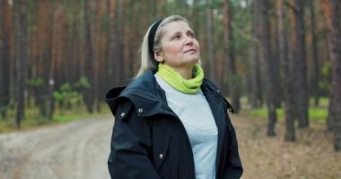 Yorgun orta yaşlı kadın sırt çantası ve minderiyle ormanın ortasında mola veriyor taze nefes alıyor yürüyüş yaparken dinleniyor dinleniyor. .