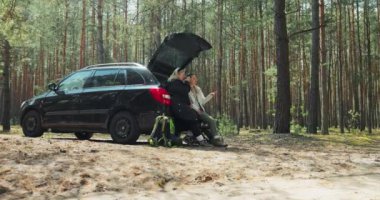 Ormanın derinliklerinde, anne ve kızı açık sandıkta oturup çay içerken sırt çantalarında paspaslarla spor çantalarından bahsediyorlar..