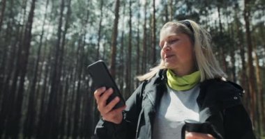 Tatmin olmuş yaşlı anne torunlarıyla telefonda konuşuyor. Hızlı bir ev ödevi yaparken doğa ve ormanı gösteriyor..