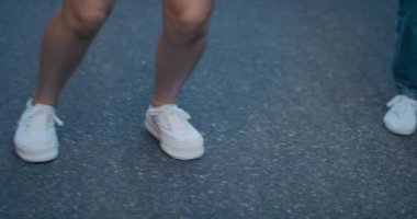 Bacaklar müziğin ritmine göre hareket ediyor. Sokak dansı konsepti. Genç kızlar ellerinde hoparlörle şehirde dans edip koreografi çalışırlar..