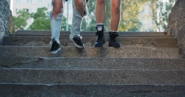 女孩们腿的特写 穿着牛仔裤和运动鞋的青少年跑下楼梯 在一个住宅区里 地下车库里黑暗的灯光 — 图库视频影像