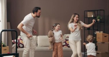 Anaokulu öğrencisi oğlu ve saç örgülü büyük kızı olan genç ebeveynler yeni apartmanlarında eğleniyorlar. Memnuniyetle dans ediyorlar. Geniş bir dairede karton kutularla müzik dinliyorlar. .