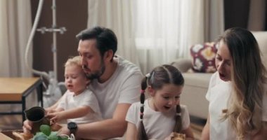 Anaokulu öğrencisi oğlu ve kızı olan genç ebeveynleri yakın plan çekimleri. Evdeki eşyalarla dolu kutuları açan çocuklar. İçeride saksı bitkileri taşınıyor..