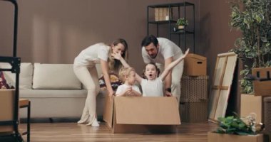 Mutlu aile kavramı, mutlu kız ve oğul kutuda oturup anne ve babasıyla yeni bir dairede oynaşıyor ve süreç konseptini değiştiriyor..