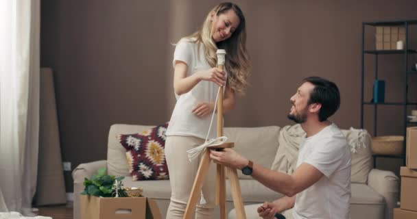 Moving Process Delighted Husband Helping Adorable Young Wife Assembling New — Stock Video