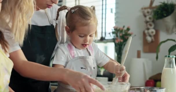 快乐的学龄前女儿 拿着木制大勺子 把家里做的面团和妈妈做的烘焙饼干 意大利面比萨饼 混合在玻璃碗里 — 图库视频影像