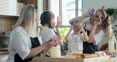 Genç sarışın anne ve yaşlı büyükanne çocuklarıyla vakit geçiriyorlar ev yapımı kurabiyeler pişiriyorlar ellerinde cam gibi farklı şekillerde kesiciler tutarak eğleniyorlar. Aile buluşması..