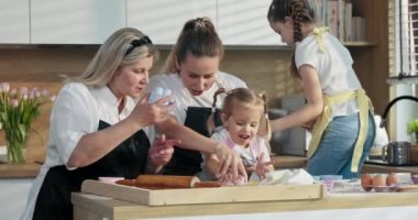 Mutlu aile, genç anne, yaşlı büyükanne ve kundakçı çocuklar ev yapımı kurabiye bisküvileri pişirmeyi öğreniyorlar. Orta yaşlı nine tepsiye farklı şekillerde kurabiye koyar..