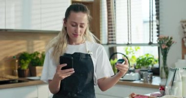 Modern mutfakta elinde kredi kartı ve cep telefonu olan mutlu genç bir anne ev yapımı hamur işleri pişirirken ev yapımı pizza bisküvileri pişiriyor..