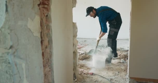 Mężczyzna Garniturze Bejsbolówce Sprząta Mieszkaniu Trakcie Remontu Zbiera Gruzy Podłogi — Wideo stockowe
