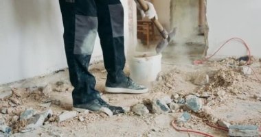 İnşaatçı, kürekle inşaat enkazı toplamakla meşgul. Ev tadilatı duvarların yıkımı.