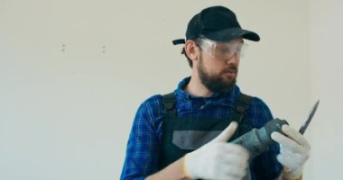 İnşaatçı duvarı yıkmak için el çekici hazırlar, matkabı uygular, apartmanı yeniler..