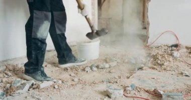 İnşaatçı, kürekle inşaat enkazı toplamakla meşgul. Ev tadilatı duvarların yıkımı.