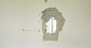 Bir adamın çekiçle vurduğu duvardaki deliğe yakın çekim. Tadilat sırasında evin, dairenin tahrip edilmesi.