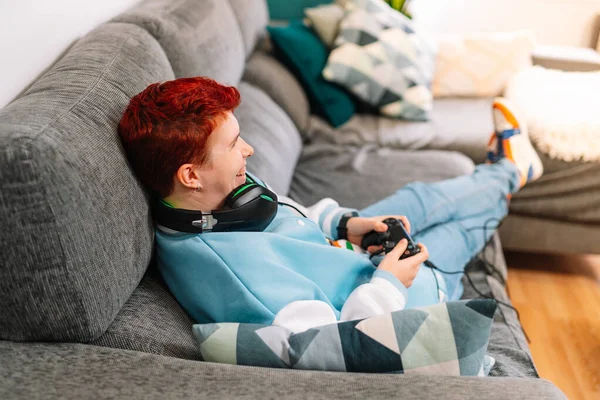 Osoba grająca w gry wideo na kanapie w salonie. Nieokreślona płeć. — Zdjęcie stockowe