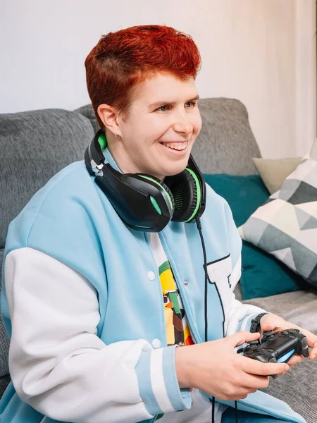 Niebinarna uśmiechnięta osoba grająca w gry wideo w salonie w domu — Zdjęcie stockowe