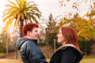 Lezbiyen çift birbirine sarılıyor. Birbirlerine romantik bir şekilde bakıyorlar. Halk parkında, kadınlar birbirlerini seviyorlar..