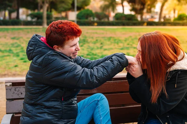 Gülümseyen lezbiyen çift halka açık bir parkta el ele öpüşürken oturup evlenme teklif ediyor..