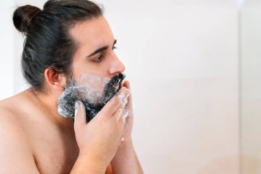 Sakallı genç adam, tıraş köpüğü yayıyor..