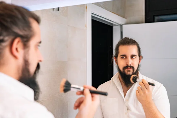 Jongeman die make-up voor de spiegel aanbrengt. Dagelijkse make-up routine in de badkamer — Stockfoto
