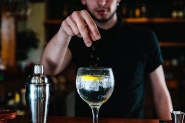 Barmen ellerinin ayrıntıları. Karışık içecekler için kristal bardağa buz koyuyorlar. Gece kulübü..
