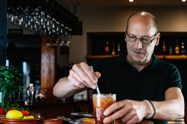 Experienced bartender shaking a cocktail in a crystal glass. Preparing a cocktail for the customers