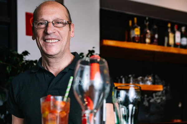 portrait of a mature waiter carrying a tray of beverages