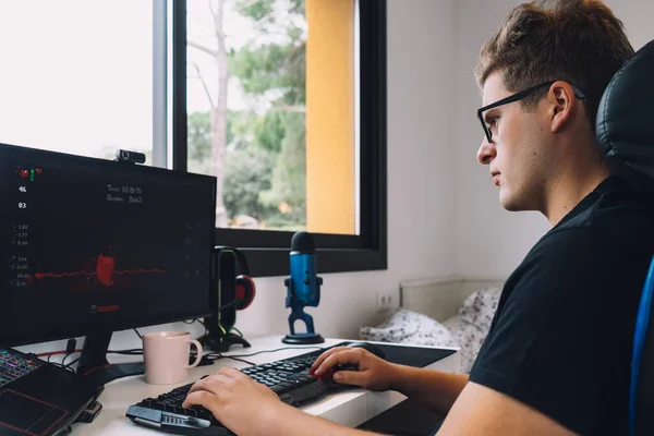 Młody człowiek pracuje jako grafik z domu na swoim komputerze. — Zdjęcie stockowe