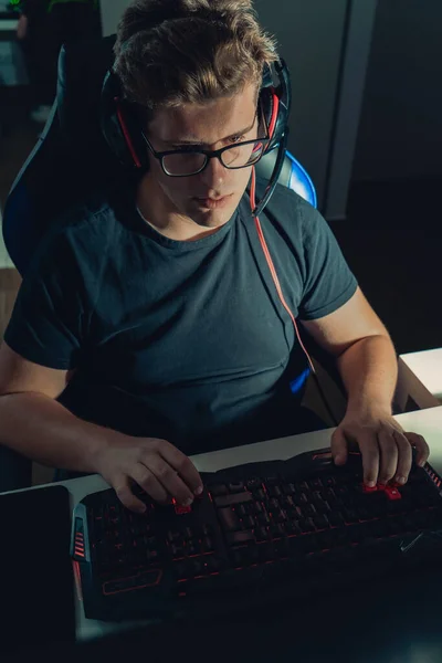 Młody blondyn grający w gry wideo, grający na laptopie w ciemności oświetlony przez ekran. — Zdjęcie stockowe