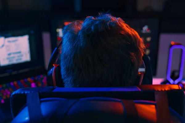 Silhouette of the back of a young man addicted to video games playing on a computer with headphones. — Stock Photo, Image