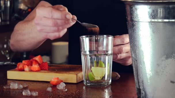 Detail rukou mladého a zkušeného číšníka, přidání hnědého cukru k přípravě mojito. — Stock video