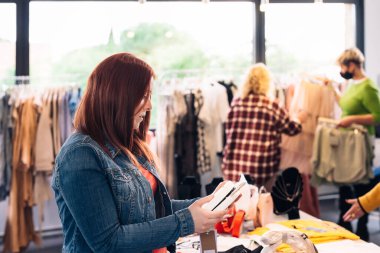 Moda mağazasından almak için raftan el çantasına bakan genç bir kadın. alışveriş kavramı. 