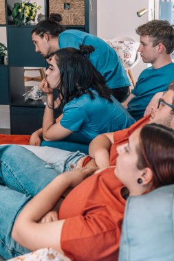 Bir grup futbol fanatiği evde, TV 'de maç izleyen gençlerin ardından üzgün. Boş zaman kavramı.