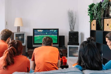 Arkadaşlar evde televizyondaki futbol maçını izlemeye konsantre oluyorlar. Genç insanlar. Boş zaman kavramı