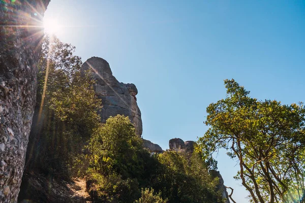 Dağ manzarası, güneş ışınları ve mavi gökyüzünün aydınlattığı orman. Montserrat Dağı İspanya. Akdeniz görüşü