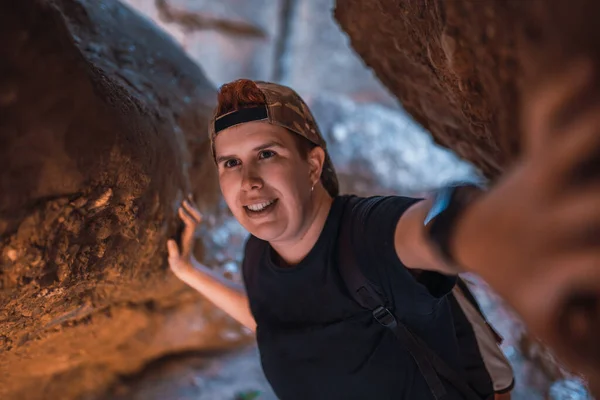 Young woman hiking, exploring the entrance of a cave. woman on vacation. young woman hiking in nature. — Stockfoto