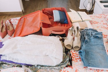 open suitcase with all the luggage ready for a trip on the bed. woman packing for a new trip. summer clothes, shoes.