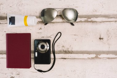 top view still life travel. Light wood background. Personal passport, sunglasses and compact camera , sun cream.