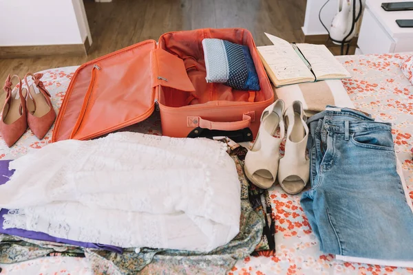 Mala aberta com toda a bagagem pronta para uma viagem na cama. mulher fazendo as malas para uma nova viagem. roupas de verão, sapatos. — Fotografia de Stock