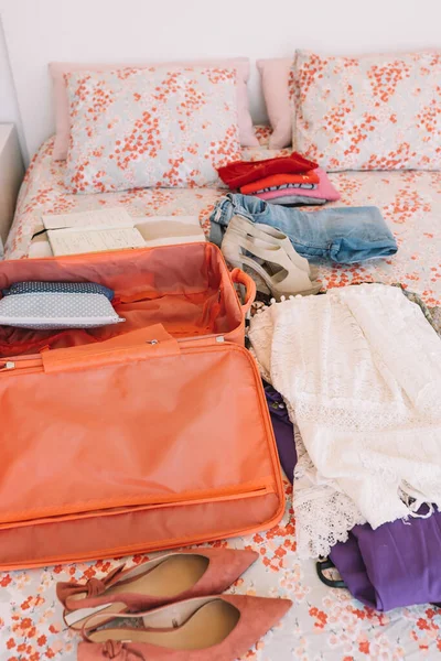 Відкрита валіза з усім багажем, готовим до поїздки на ліжко. жінка готується до нової подорожі. вертикальний . — стокове фото