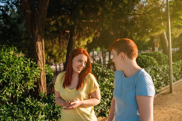 two young people chatting and strolling happily, in a public park in the city at dawn. young girls enjoying the summer outside. concept of friendship and companionship.natural light, sunshine, summer