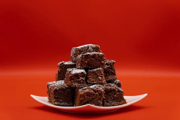 Brownie 'ler beyaz tabakta ve kırmızı arkaplanda