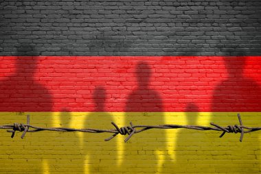 Mülteciler Almanya 'ya göç ediyor. Yasadışı göçmenlerin silueti. Avrupa Birliği göç politikası. Alman bayrağı tuğla duvara boyanmış.