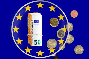 Currency of European Union over European Economic Community Flag. EUR is the official currency of the European Union. View through magnifying glass